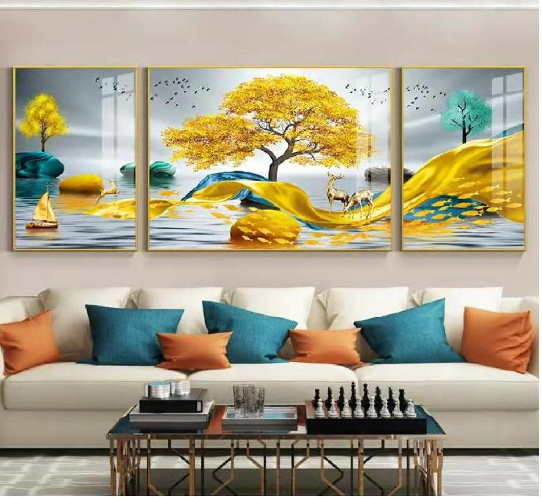 Three-piece set of a golden tree over a lake with stags and sailboats, above a cream sofa with teal and orange cushions